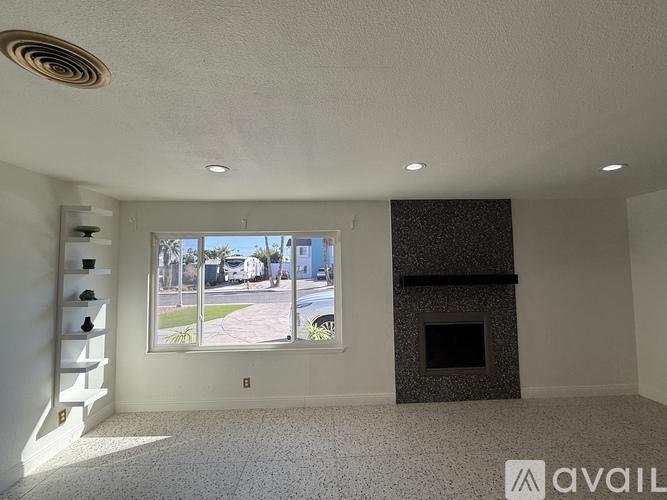 A room with a fireplace and a window showing a street view.