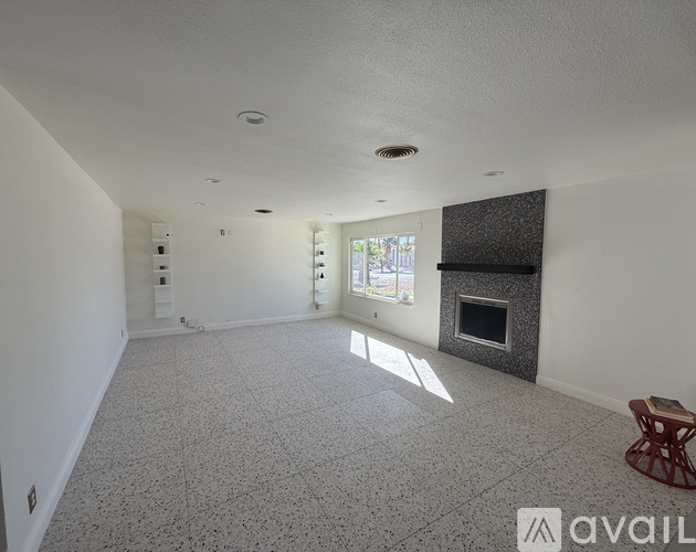 A spacious living room with a fireplace and a textured floor.