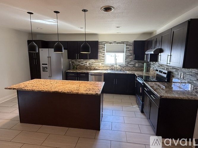 A kitchen with granite countertops and black cabinets.