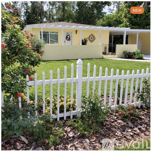 A yellow house with a white picket fence in front.