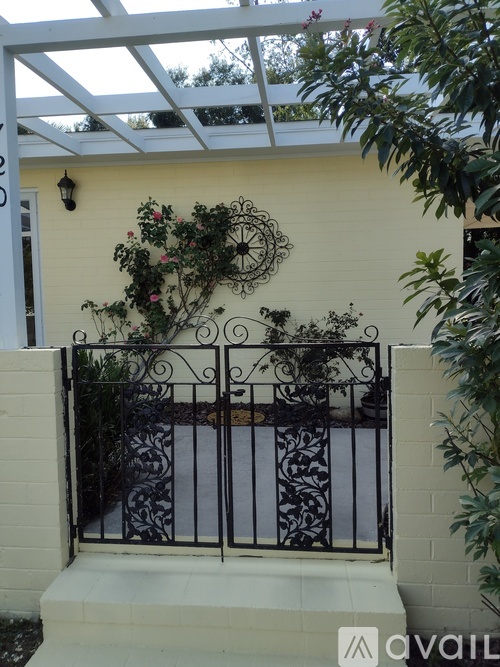 A white house with a black iron fence and a hanging plant.