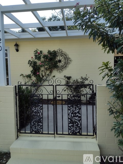 A white house with a black iron fence and a hanging plant.
