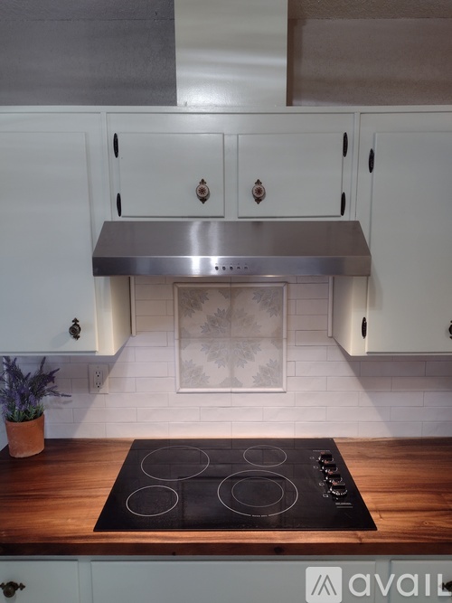 A kitchen with a stove top oven and white cabinets.
