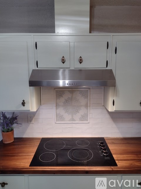 A kitchen with a stove top oven and white cabinets.