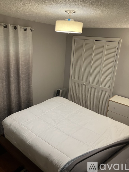 A bedroom with a white bedspread and a grey headboard.