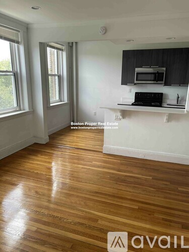 A kitchen with wooden floors and a black microwave above the counter.