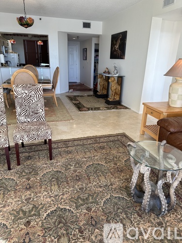 A living room with a zebra print chair and a glass coffee table.