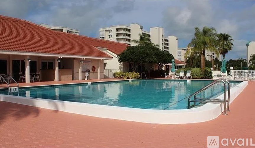 A swimming pool with a red tiled roof and a building in the background.