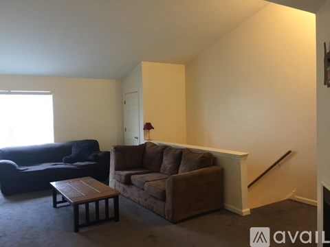 A living room with a brown couch and a black couch.