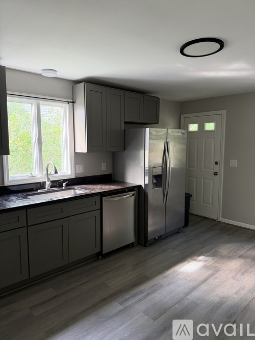 A kitchen with a refrigerator, sink, and cabinets.