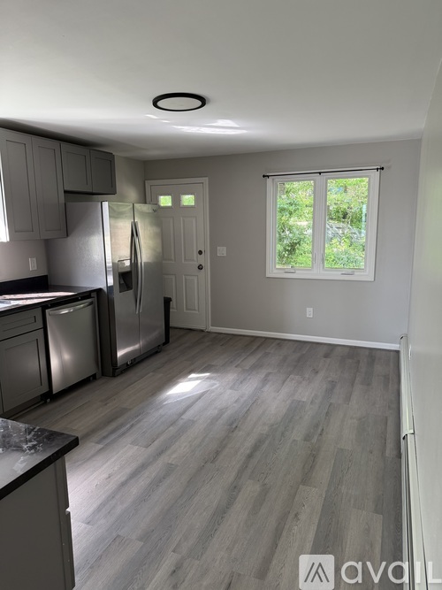 A kitchen with a refrigerator, dishwasher, and a window.