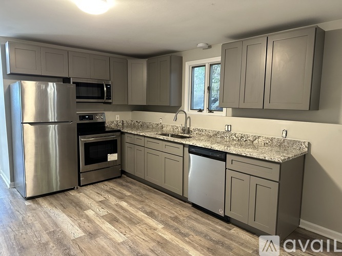 A kitchen with a refrigerator, oven, microwave, sink, and cabinets.