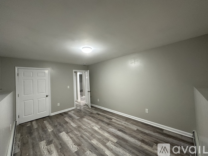 A room with wood flooring and a white door.