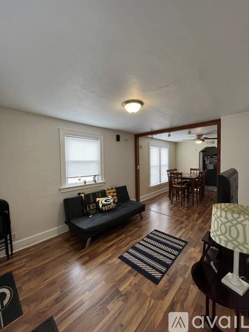 A living room with a black couch and wooden floors.