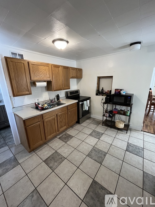 A kitchen with wooden cabinets and a tiled floor.