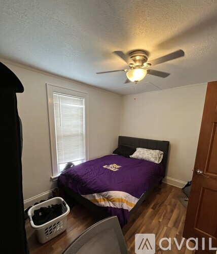 A bedroom with a bed, a ceiling fan, and a window.
