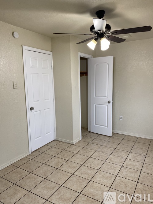 A room with a ceiling fan and two doors.