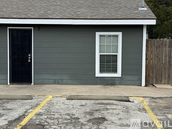 A grey building with a black door and a window.