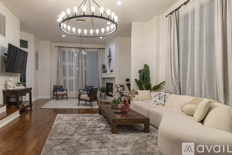 A living room with a white couch, a wooden coffee table, and a chandelier.