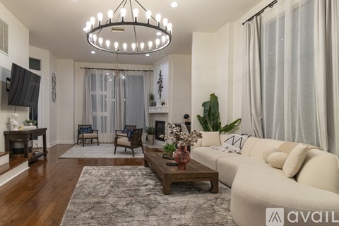 A living room with a white couch, a wooden coffee table, and a chandelier.