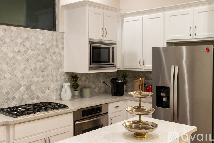 A kitchen with white cabinets and a stainless steel refrigerator.