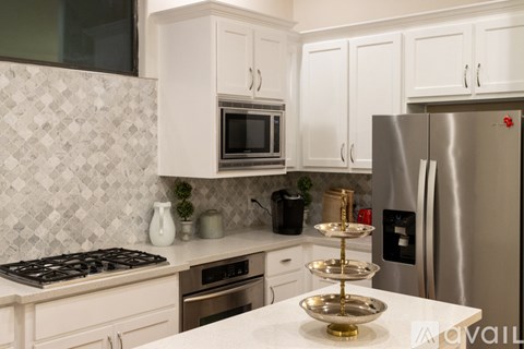 A kitchen with white cabinets and a stainless steel refrigerator.