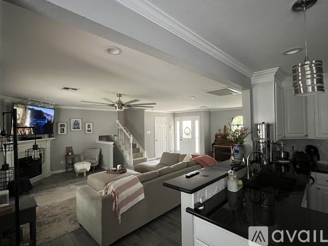 A living room with a couch, a television, and a kitchen area with a sink and stove.