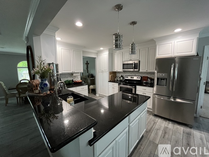 A modern kitchen with a black countertop and stainless steel appliances.