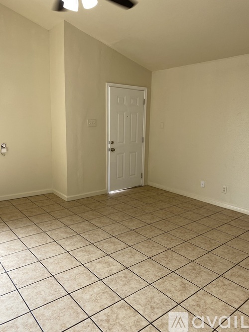 A room with a white door and tiled floor.
