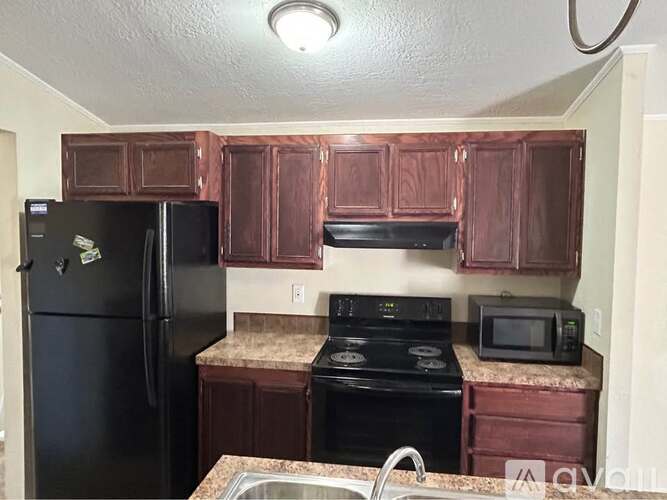 A kitchen with brown cabinets and black appliances.