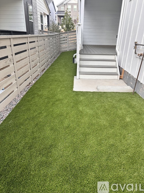 A small backyard with a wooden fence and artificial grass.