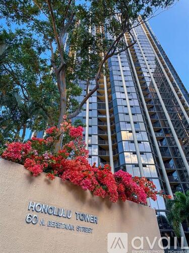 The Honolulu Tower is a tall building with a sign in front of it.