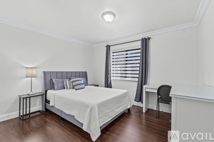 A bedroom with a bed, desk, and chair.