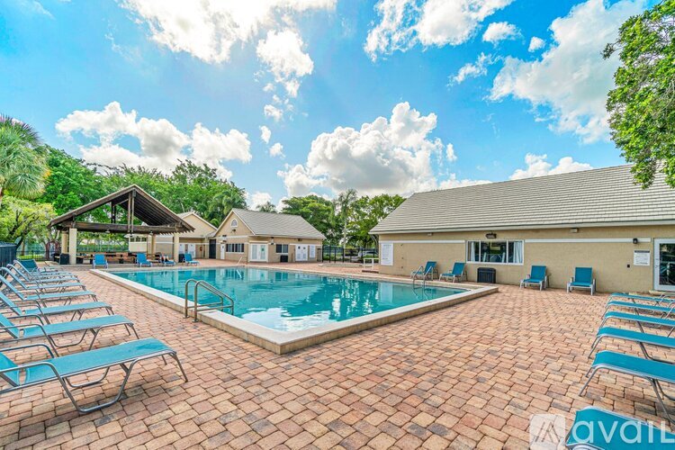 A pool surrounded by lounge chairs in front of a house.
