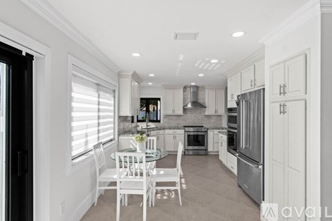 A modern kitchen with white chairs and appliances.
