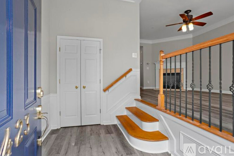 A staircase with a wooden handrail and white steps leads to a second floor.