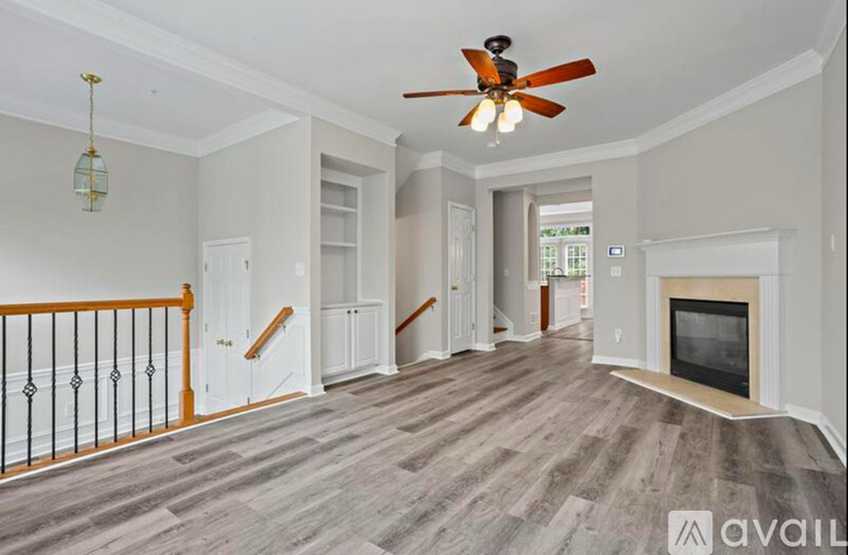 A spacious living room with a fireplace and a ceiling fan.