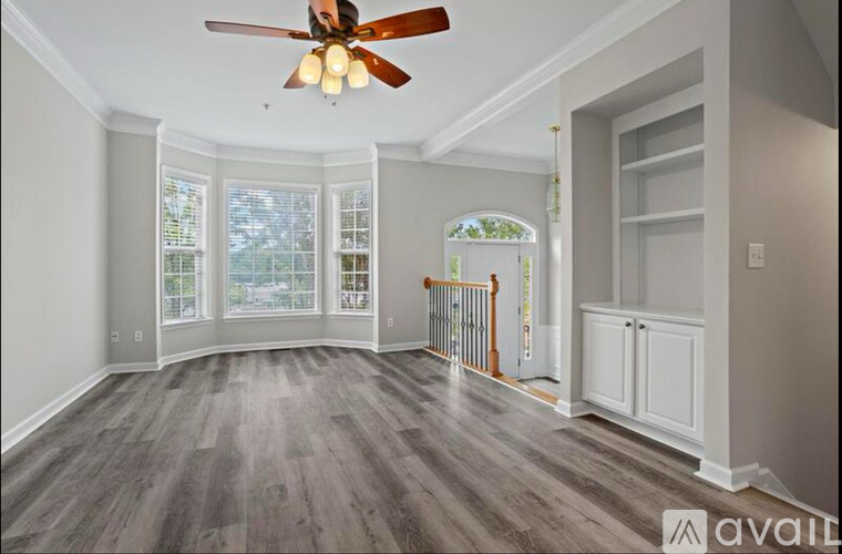 A spacious room with a ceiling fan and wooden flooring.
