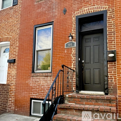 A brick building with a black door and a window with a painting of a tree.