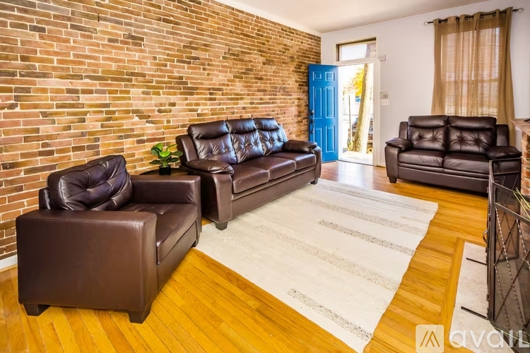 A living room with brown leather furniture and a brick wall.
