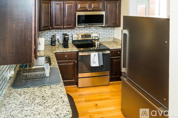 A kitchen with a granite countertop and a stainless steel refrigerator.