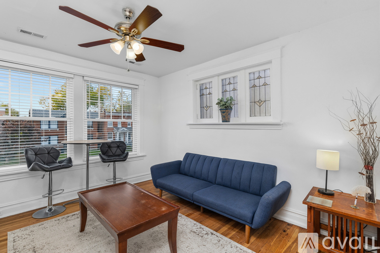 A living room with a blue sofa, a wooden table, and a ceiling fan.
