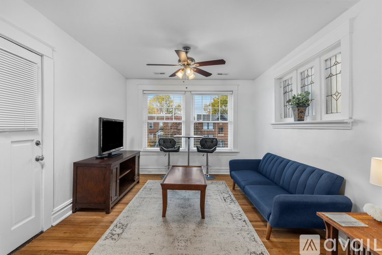 A living room with a blue couch, a wooden coffee table, and a ceiling fan.