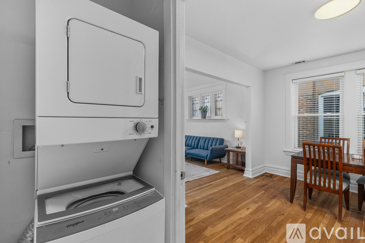 A kitchen with a dishwasher and a blue sofa in the living room.