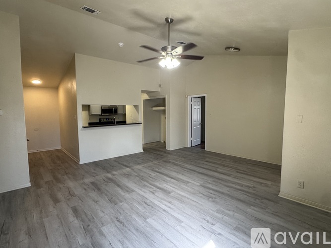 A spacious room with a ceiling fan and lighting fixtures.