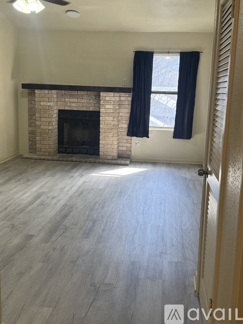 A room with a fireplace and a window with blue curtains.