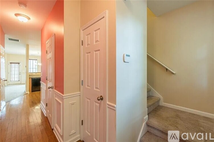 A hallway with a white door and a staircase on the right.