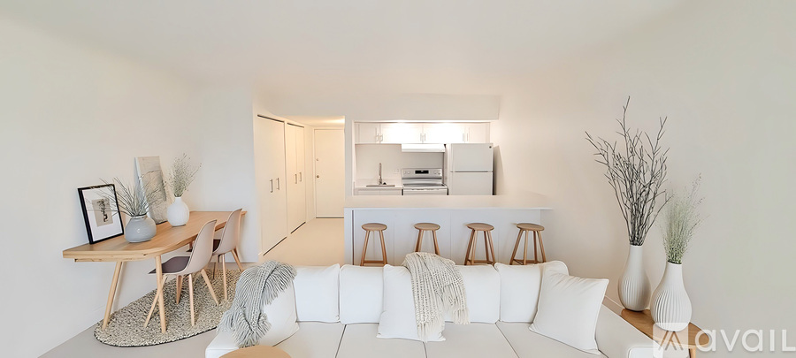 A living room with a white couch, a wooden table, and a bar area with stools.