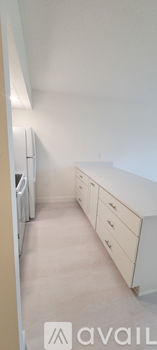 A white kitchen with a refrigerator and cabinets.