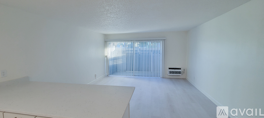 A spacious room with a window and a small cabinet.